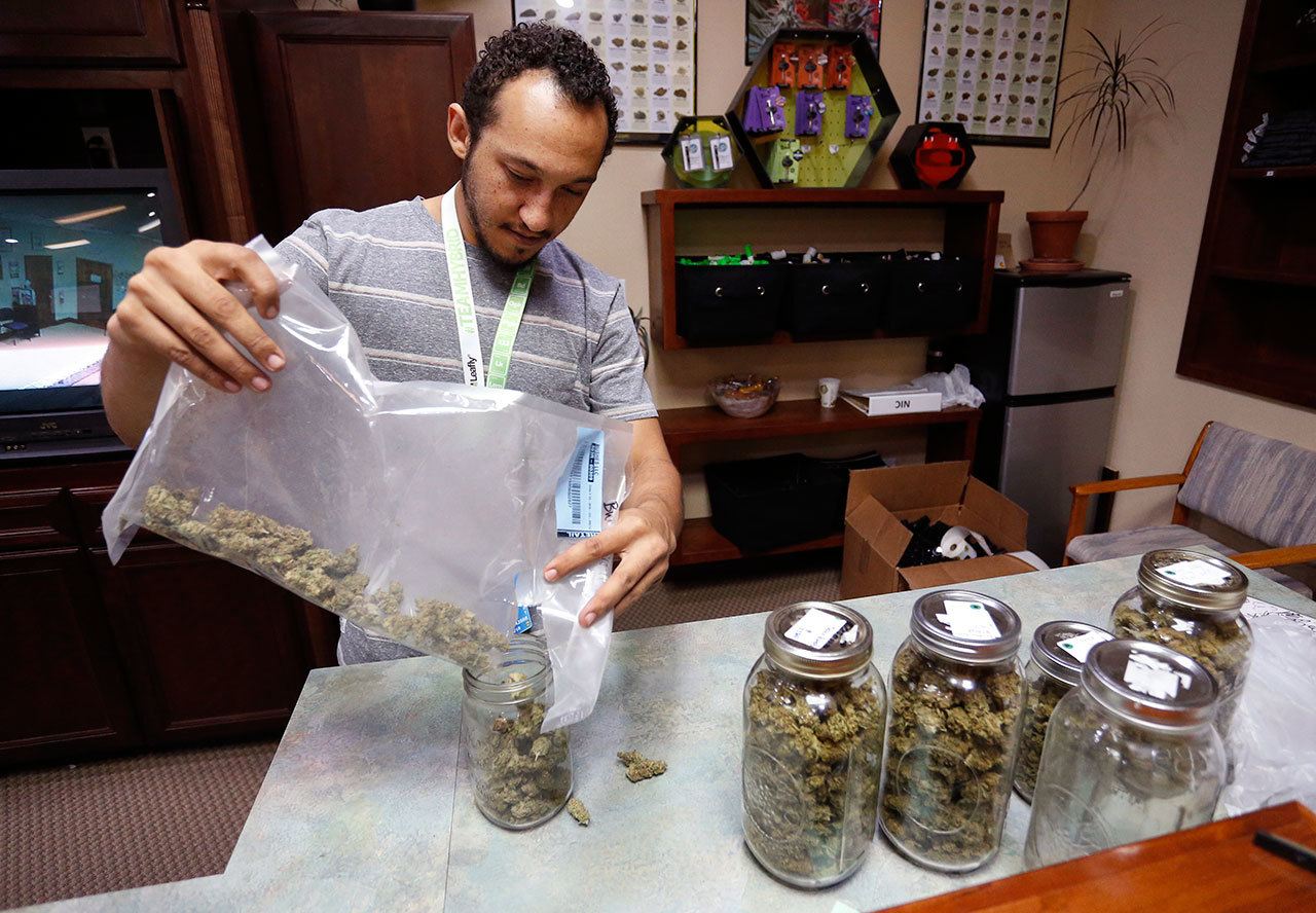 Budtender Miles Claybourne sorts strains of marijuana for sale into glass containers at The Station, a retail and medical cannabis dispensary, in Boulder, Colo., on Thursday. (Brennan Linsley/The Associated Press)