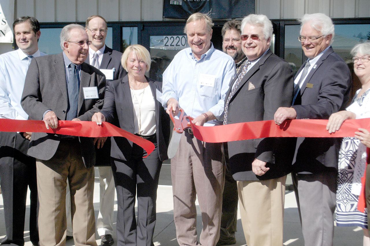 State Rep. Steve Tharinger, center, cuts the ribbon Thursday morning during a ribbon-cutting ceremony commemorating the opening of the Composite Recycling Technology Center at 2220 W. 18th St. in Port Angeles. From left are Nathan West, Port Angeles Community and Economic Development director; Port Angeles Mayor Patrick Downey; David Walter, CRTC board chair; Connie Beauvais, Port of Port Angeles District 3 commissioner; Tharinger; Norm Nelson, Peninsula College advanced manufacturing and composites instructor; Robert Larsen, CRTC CEO; and Luke Robins, Peninsula College president. (Chris McDaniel/Peninsula Daily News)