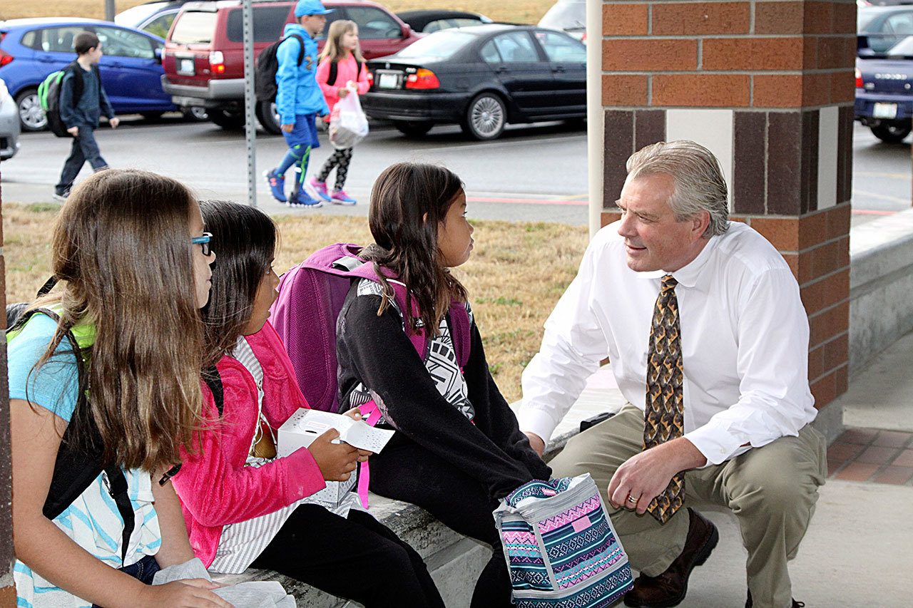 Jay Sparks, the new principal at Dry Creek Elementary School in Port Angeles, greets returning students outside the school Thursday, the first day of school. From left are Alisa Waterhouse, 11; McKenzie Moses, 8; and Tatum Moses, 9. (Dave Logan/for Peninsula Daily News)