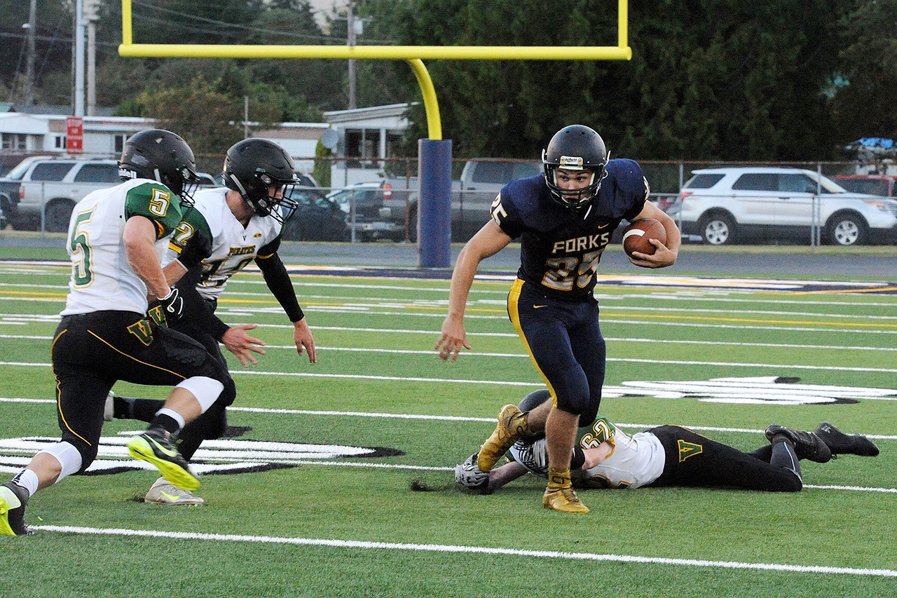 Lonnie Archibald/for Peninsula Daily News Forks running back Kenny Gale heads upfield after shaking off an ankle tackle during the Spartans’ season-opening win against Vashon.