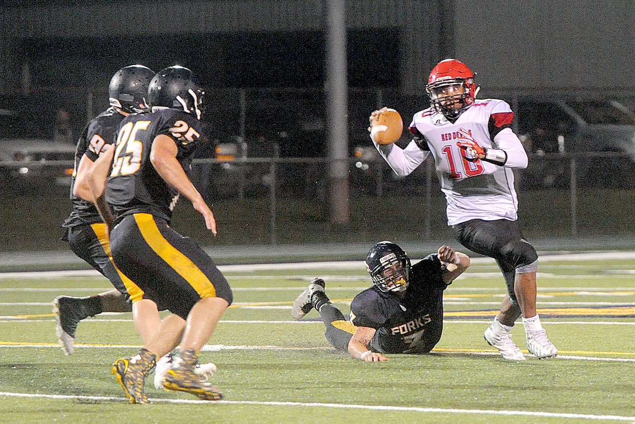 Lonnie Archibald/for Peninsula Daily News Neah Bay’s Rwehabura Munyagi Jr.(10) is pressured by Forks’ (from left) Jack Dahlgren, Kenny Gale, and Brett Moody. Munyagi scored on a pass reception and an interception return, threw the game-tying touchdown and scored the game-winner on a QB sneak in overtime.