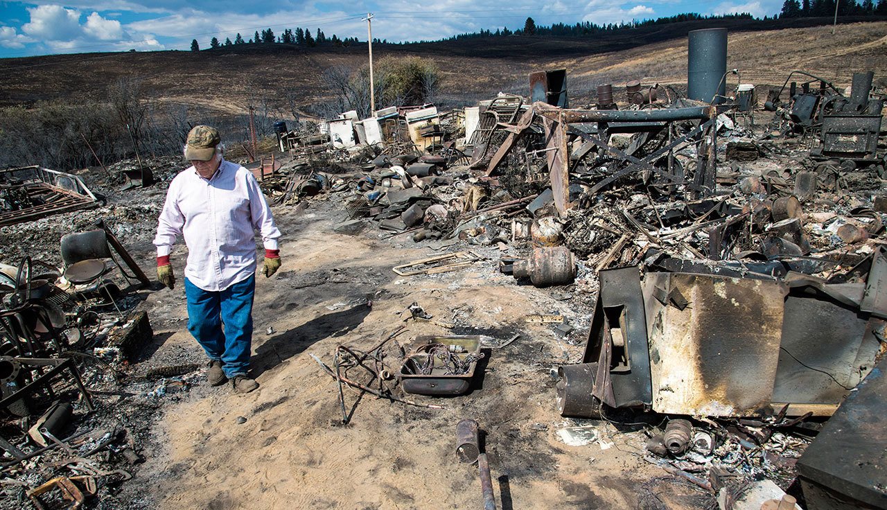 Vern Scherrer, 83, walks through the burned remains of his rental property near Wellpinit on Aug. 25. (Colin Mulvany/The Spokesman-Review via AP)