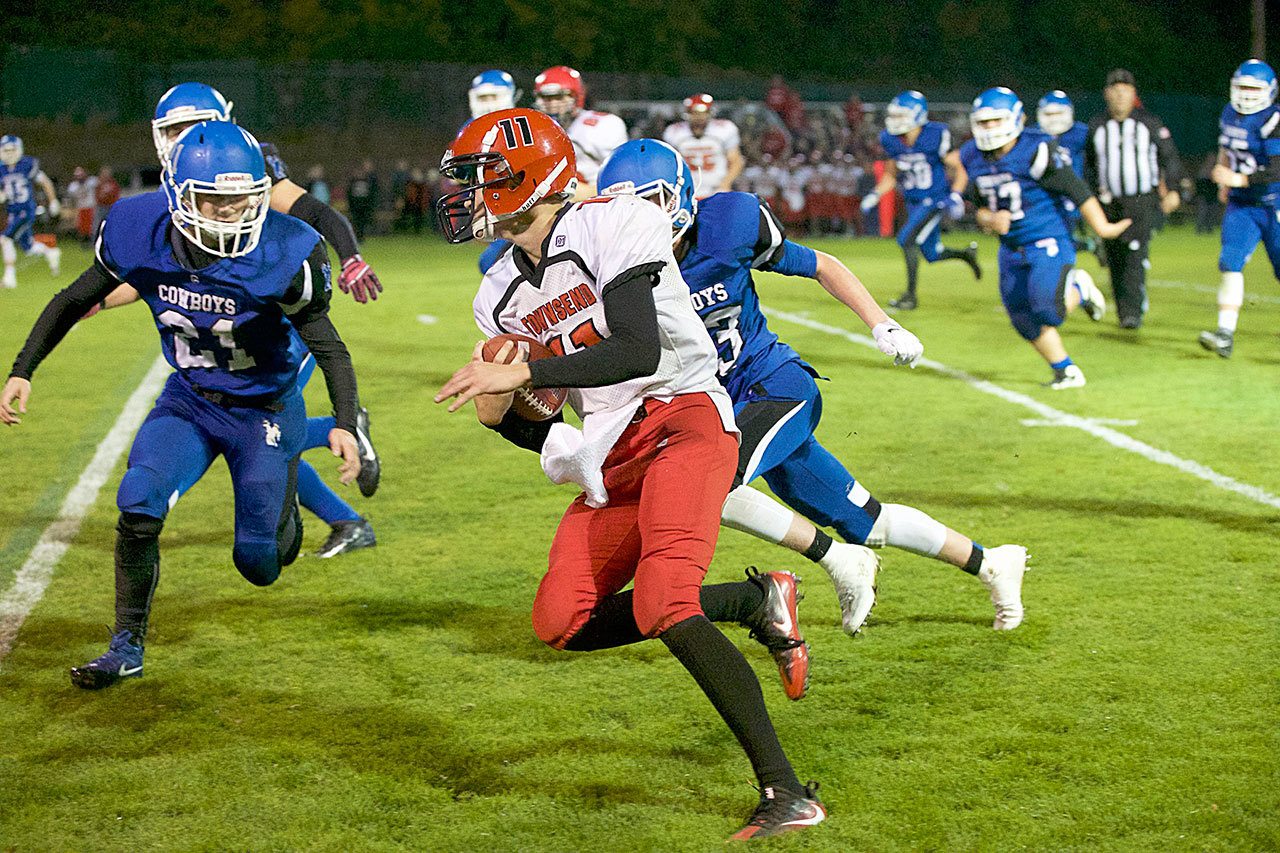 Steve Mullensky/for Peninsula Daily News Port Townsend’s Berkley Hill tries to evade the tackles by Chimacum’s Domenick Zack, 21 and Issac Purser, 83, during the Redhawks’ 55-6 win over the Cowboys. Hill scored six touchdowns in the win.