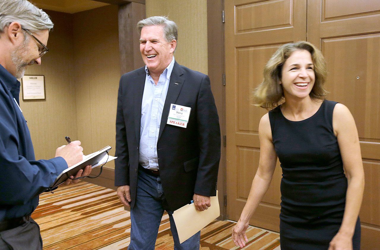 The Associated Press Democrat Hilary Franz, right, and Republican Steve McLaughlin, center, laugh Sept. 14 after McLaughlin won a coin toss made by Jason Hagey, left, vice president of Communications for the Association of Washington Business, before the two debated at the AWB Policy Summit in Cle Elum.