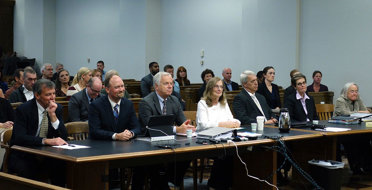 Attorneys representing family members and survivors of the Oso landslide, at the left table, and attorneys representing the Grandy Lake Forest Associates timber company, at the right table, react as King County Superior Court Judge Roger Rogoff announces in Seattle that a settlement had been reached in a lawsuit brought by survivors and family members of people killed in the slide. (Ted S. Warren/The Associated Press)