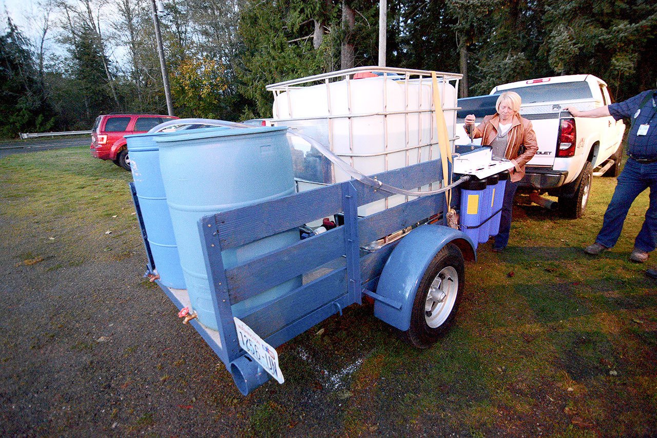 Connie Beauvais, Crescent Water Association manager, pulls a lever on the Joyce Emergency Planning and Preparation group’s portable hand-powered water purification system Monday. (Jesse Major/Peninsula Daily News)