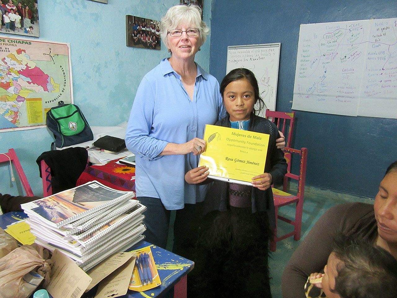 Judith Pasco, Mujeres de Maiz Opportunity Fund of Clallam County board chair, presents Rosa, a 5th grader, with a scholarship during a visit to Chiapas, Mexico in August. (Linda Finch)                                Judith Pasco, Mujeres de Maiz Opportunity Fund of Clallam County board chair, presents Rosa, a fifth-grader, with a scholarship during a visit to Chiapas, Mexico, in August. (Linda Finch)