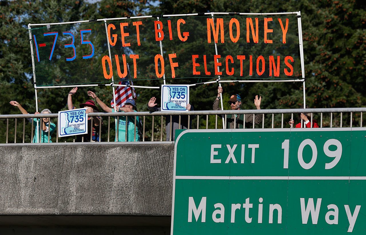 The Associated Press Supporters of Initiative 735 hold a banner above the Interstate 5 freeway during the evening commute in Lacey.