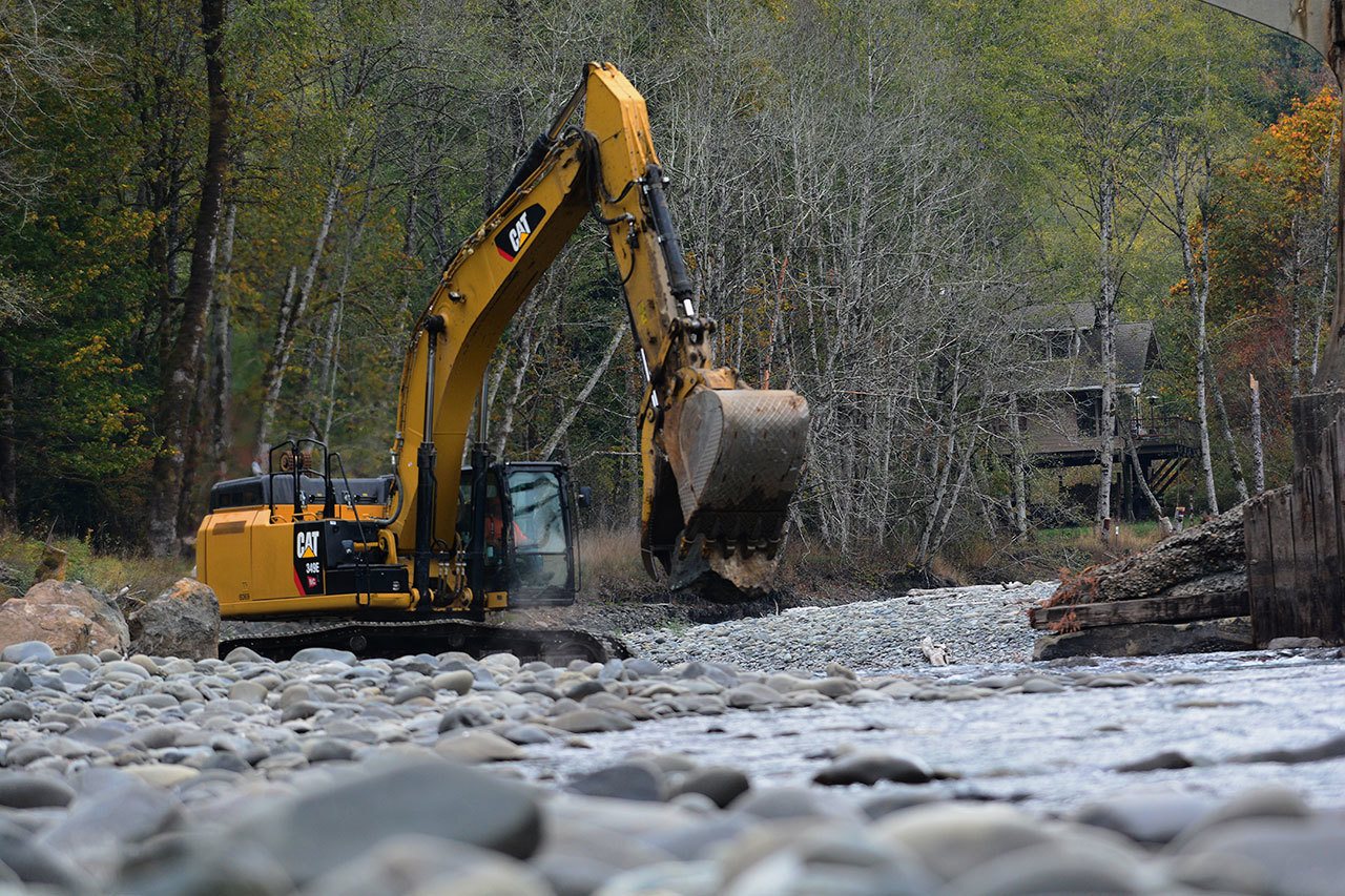 Crews work Tuesday to place large boulders around the base of each of the piers of the Elwha River bridge on U.S. Highway 101 to slow the rate of erosion. (Jesse Major/Peninsula Daily News)