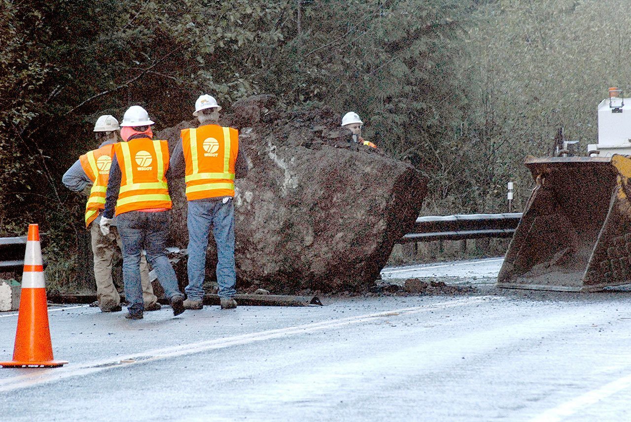 State Department of Transportation workers prepare to push a refrigerator-sized boulder over the embankment over Lake Crescent on U.S. Highway 101 on Wednesday morning. (Keith Thorpe/Peninsula Daily News)