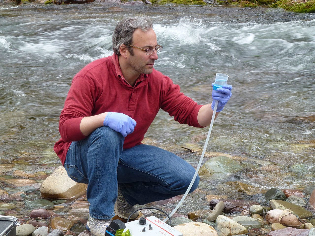 Michael K. Schwartz filters 5 liters of water to concentrate DNA on a filter to be analyzed at the National Genomics Center for Wildlife and Fish Conservation, on Rattlesnake Creek near Missoula, Mont., in 2014. (Kellie Carim/U.S. Forest Service via AP)