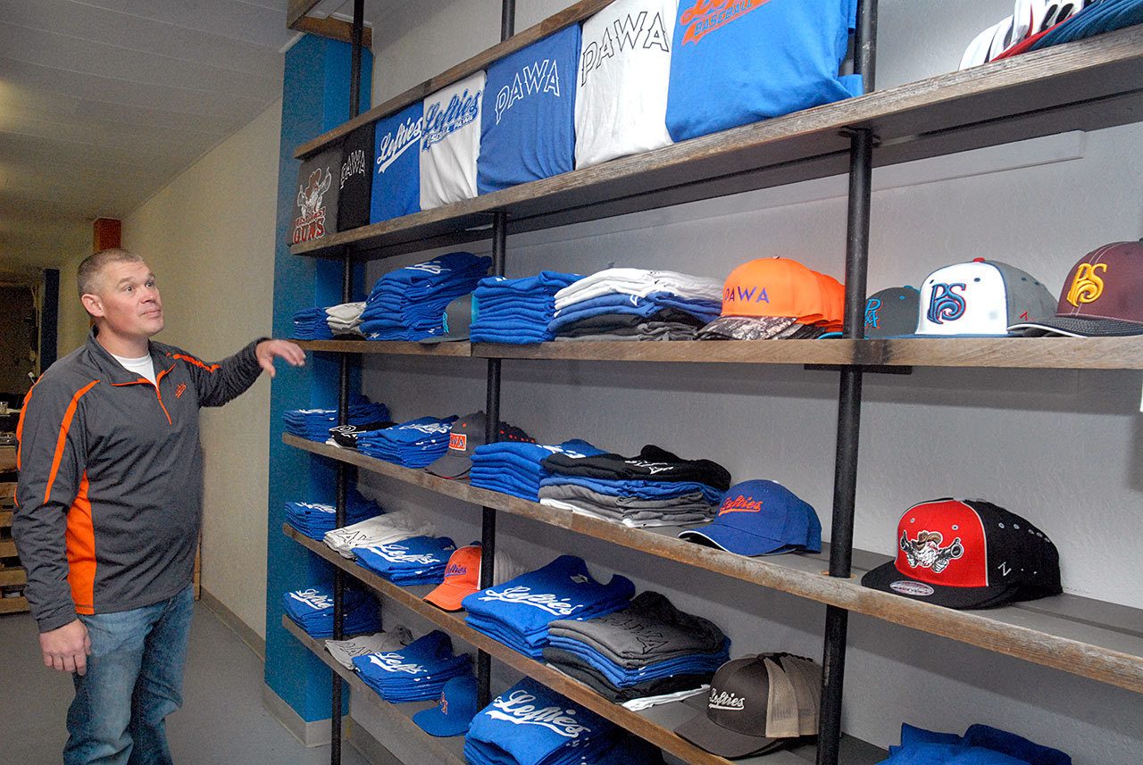 Keith Thorpe/Peninsula Daily News Lefties baseball owner Matt Acker looks over a shelf of team t-shirts and caps at the franchise’s storefront at 117 W. First St., in downtown Port Angeles on Tuesday.
