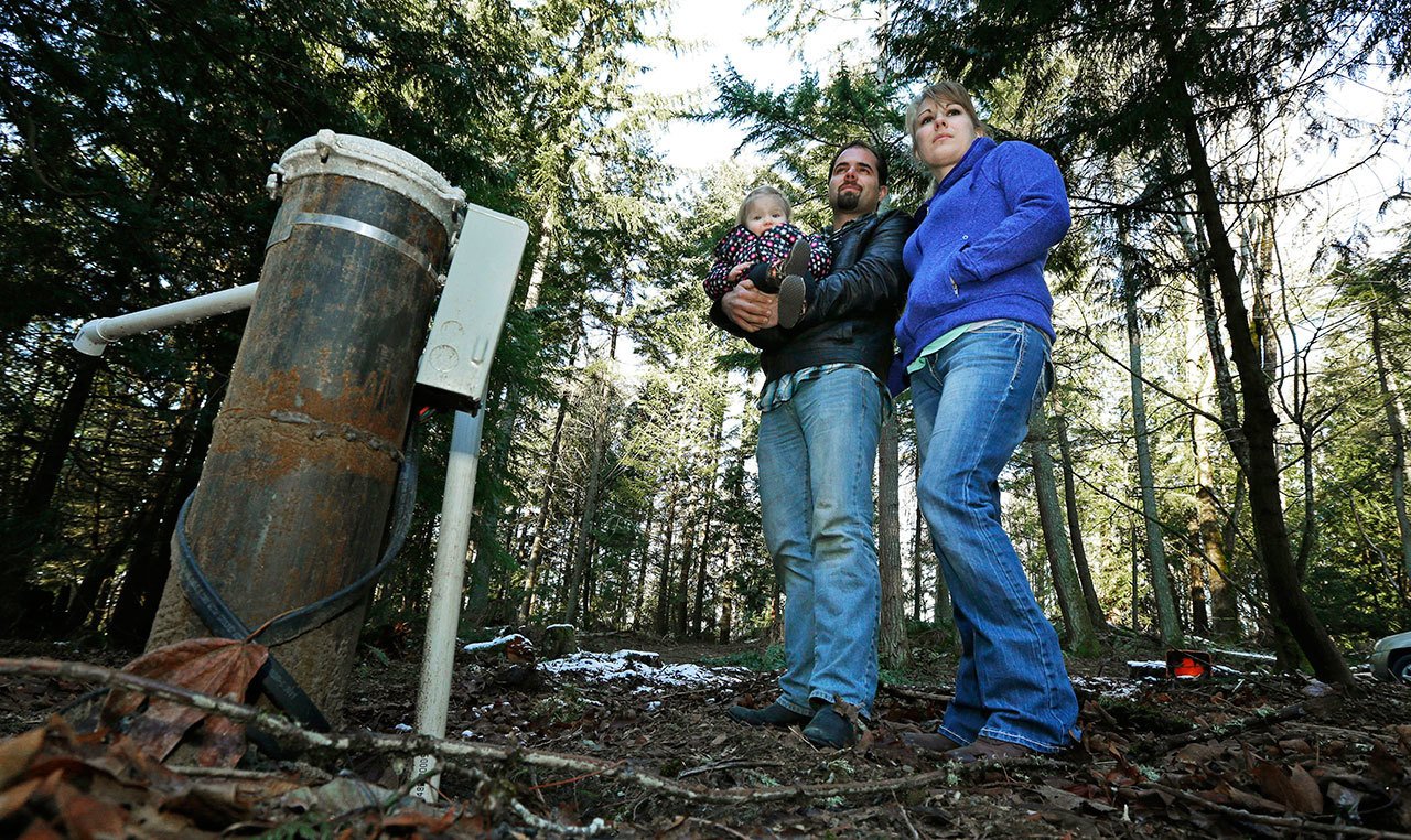 Bud Breakey and his wife Deborah pose for a photo with their daughter Kaylin, 15 months, by the well they paid to drill on property they own near Bellingham. (Ted S. Warren/The Associated Press)