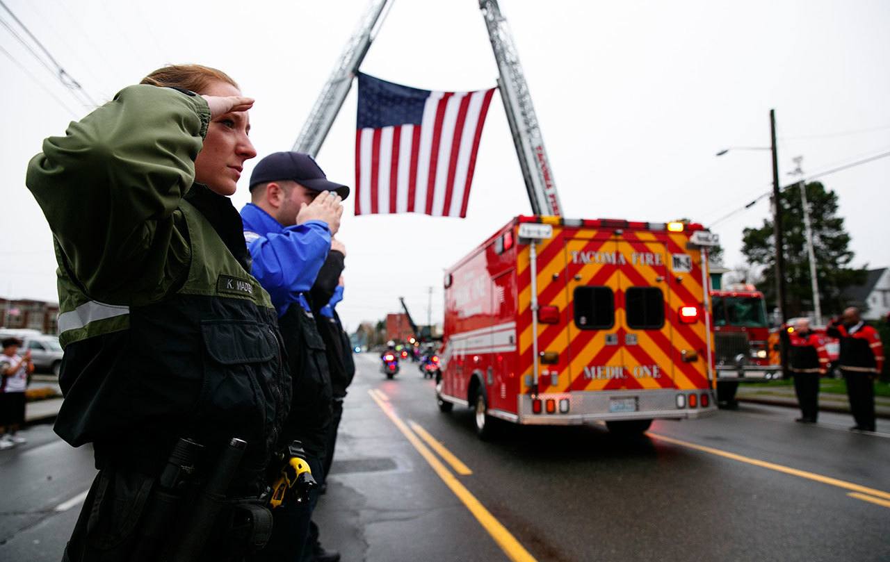 Tacoma Police Department animal control officer Kate Madden salutes during the procession for Tacoma Police Officer Reginald “Jake” Gutierrez on Friday in Tacoma. Crowds gathered to pay respects to Gutierrez, who died Wednesday after being shot while responding to a domestic violence call. (Erika Schultz/The Seattle Times via AP)