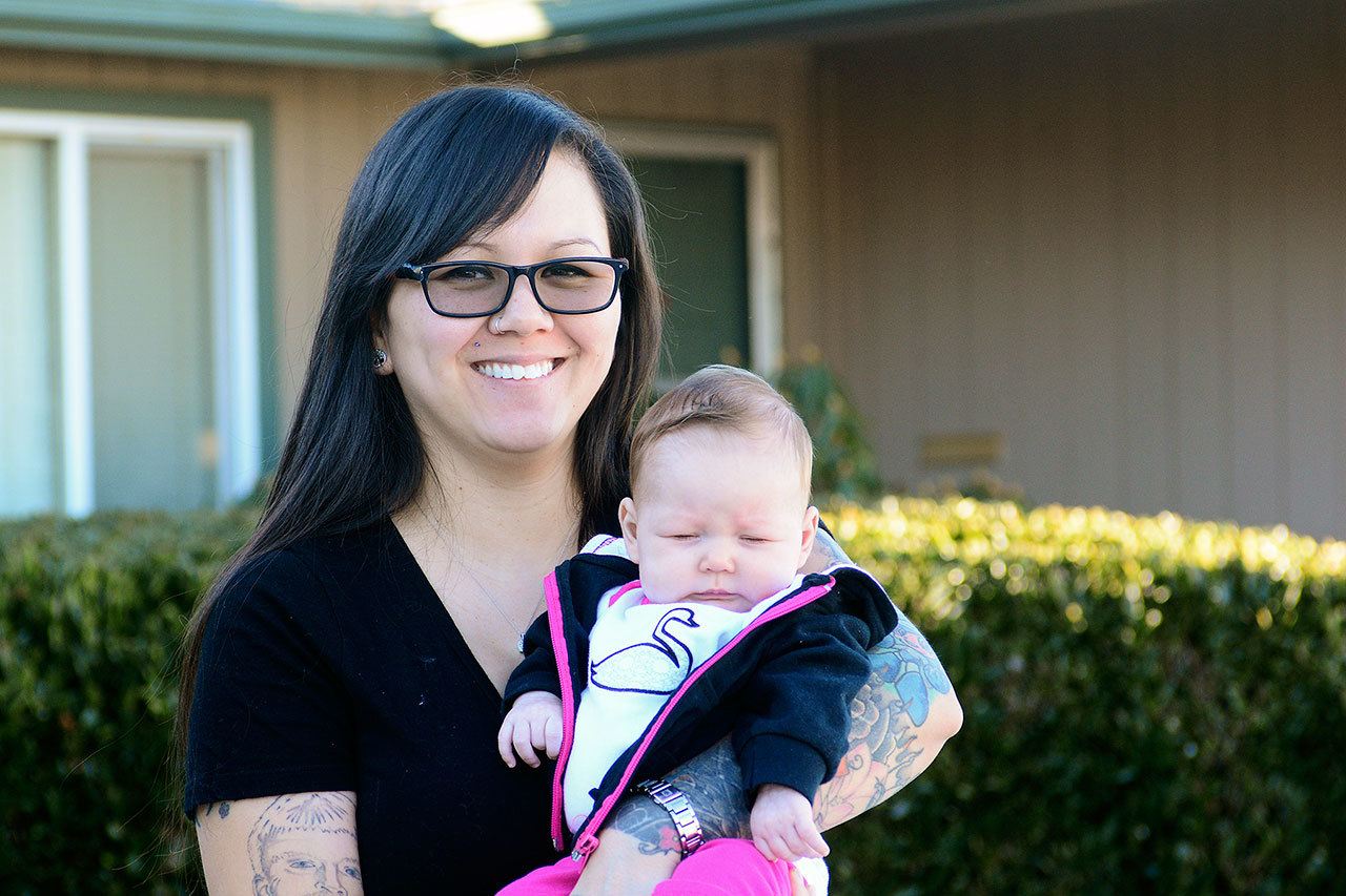 Sarah Hayward of Port Angeles holds her 2-month-old daughter, Penelope Hayward, days after she says a man saved her family from certain death on New Year’s Day. (Jesse Major / Peninsula Daily News)