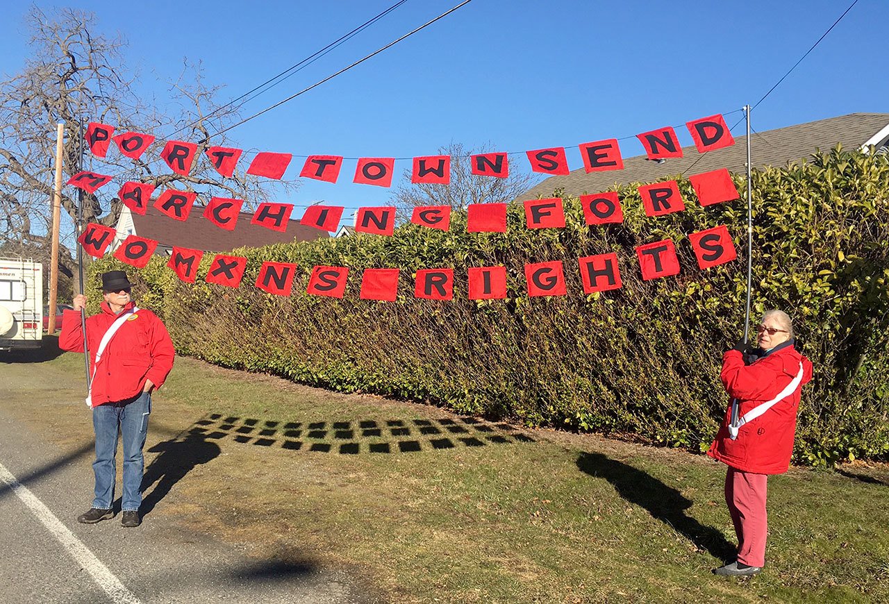 Anita and Mike Edwards hold up a Port Townsend sign that will be used in the Seattle Womxn’s March on Saturday. (Annemarie Mende)