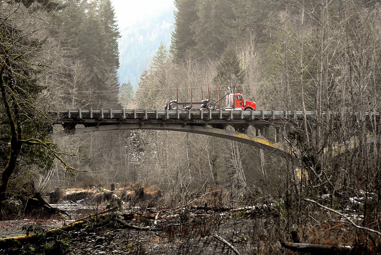 A logging truck makes its way across the U.S. Highway 101 bridge over the Elwha River west of Port Angeles in December. (Keith Thorpe/Peninsula Daily News)