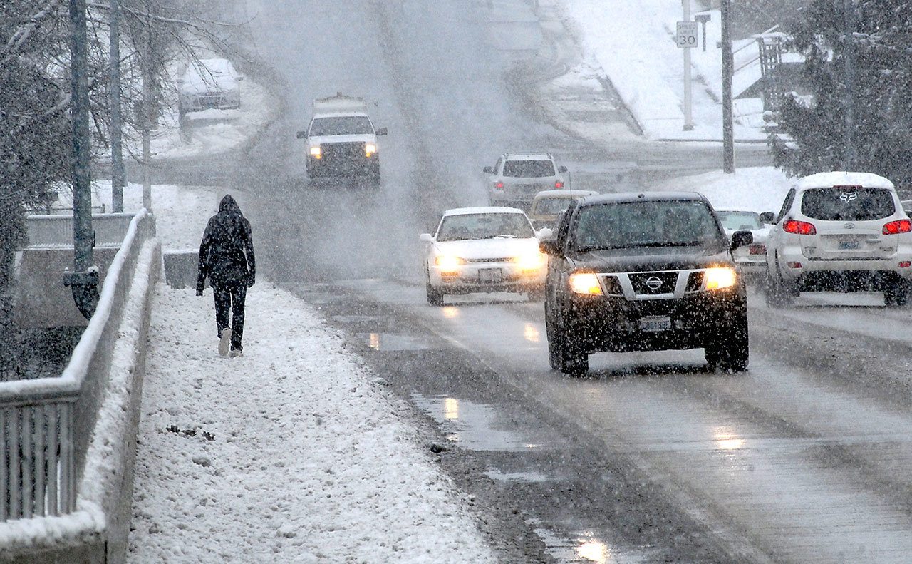 A pedestrian crosses the Eighth Street Bridge over Valley Creek as snow falls across Port Angeles on Tuesday morning. Snow from the day and night before led to icy conditions Tuesday on many streets and highways across the North Olympic Peninsula. (Keith Thorpe/Peninsula Daily News)