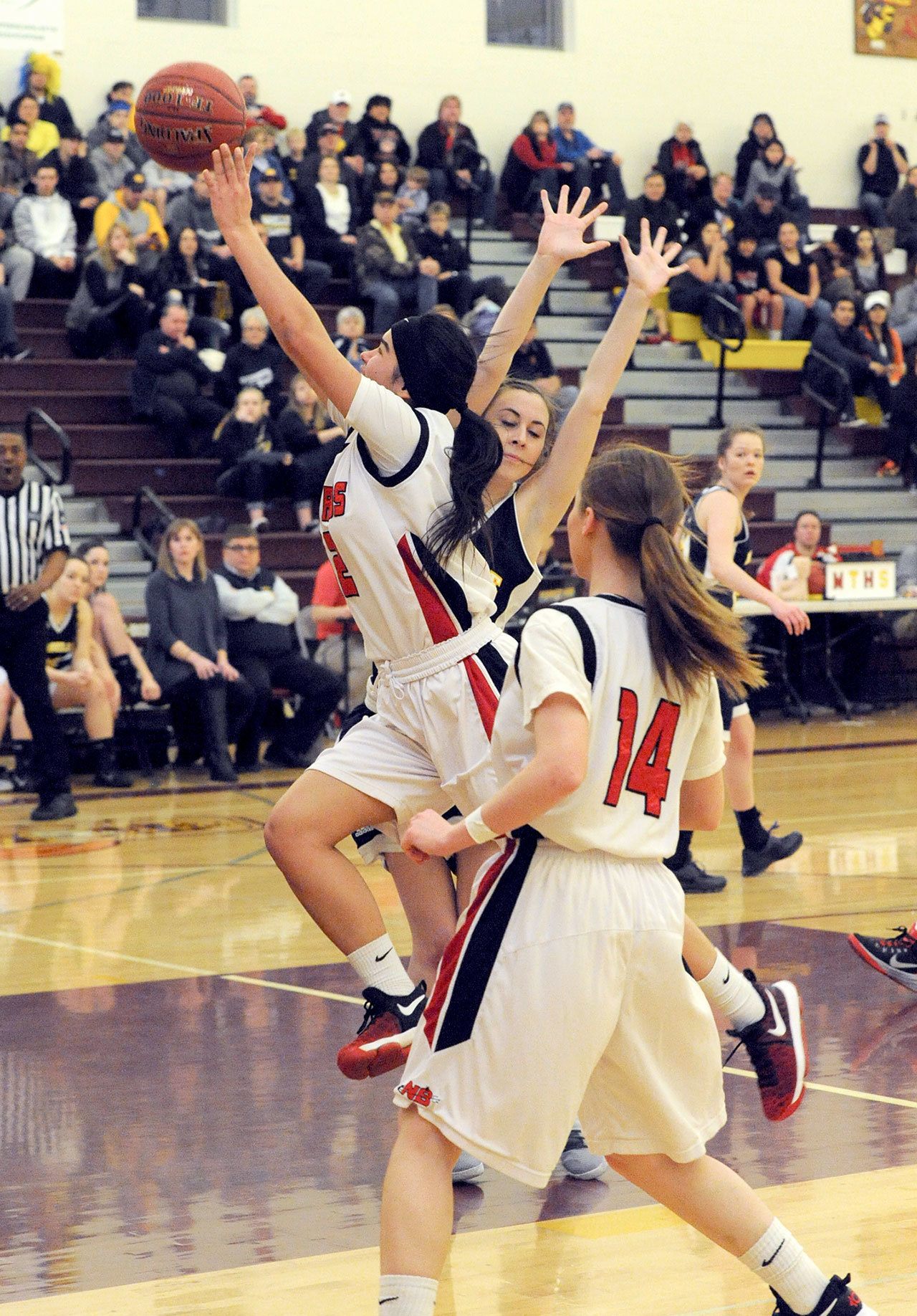 Lonnie Archibald/for Peninsula Daily News Neah Bay’s Vonte Aguirre drives past Naselle’s Taylor Ford for a basket during the Red Devils 58-39 Class 1B state regional win at Mount Tahoma High School on Saturday. Looking on for Naselle is Lilli Zimmerman (14) and the Red Devils’ Cheyenna Svec (14).
