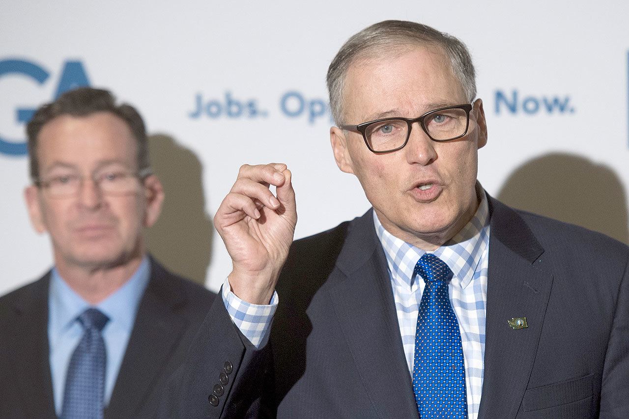 Democratic Governors Association Chairman Dannel Malloy of Conn., left, watches as Gov. Jay Inslee speaks with reporters following a DGA meeting at the National Governors Association Winter Meeting in Washington, D.C. (Cliff Owen/The Associated Press)