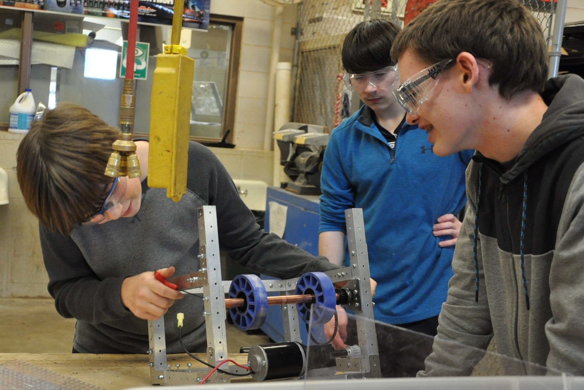 Sequim High School Robotics students Nick Charters, Riley Chase and Josh King, from left, survey a robotic component to decide on the best approach. The students are constructing a robot that is able to perform a prescribed task for competition in early March. (Patsene Dashiell)
