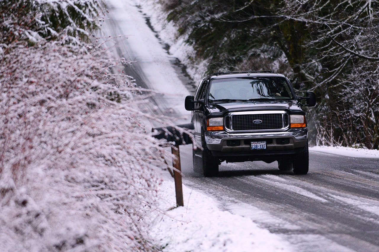 A vehicle travels on the snow-covered Dan Kelly Road west of Port Angeles on Sunday. (Jesse Major/Peninsula Daily News)