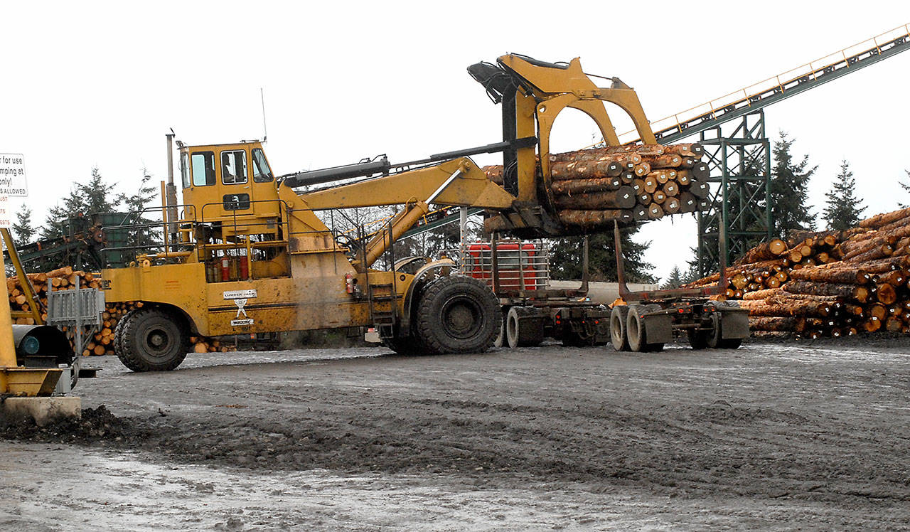 A loader lifts logs from a truck at the Merrill & Ring log yard on Tuesday near William R. Fairchild International Airport. (Keith Thorpe/Peninsula Daily News)