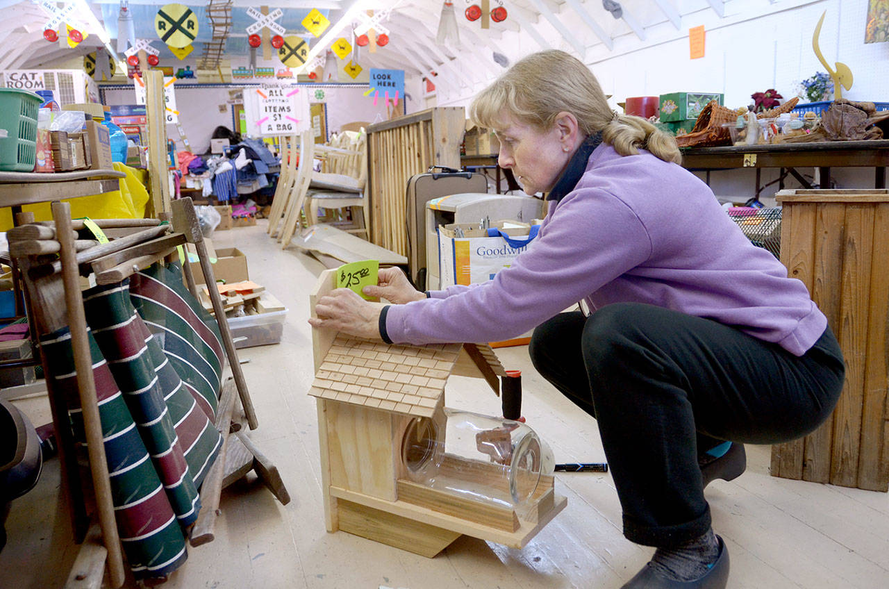 Laurie Hampton prices items for Saturday’s community garage sale and flea market, which raises money for the Jefferson County Fairgrounds. (Cydney McFarland/Peninsula Daily News)