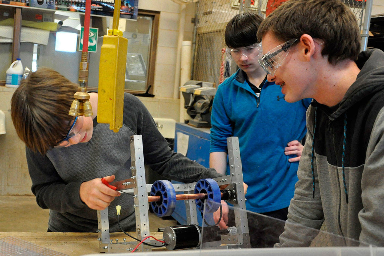 Sequim High School robotics students, from left, Nick Charters, Riley Chase and Josh King, survey a robotic component before a competition in early March. The team qualified for the FIRST Robotics Competition world championship in Houston and will take their robot there to compete against teams from across the globe. (Patsene Dashiell/Sequim School District)