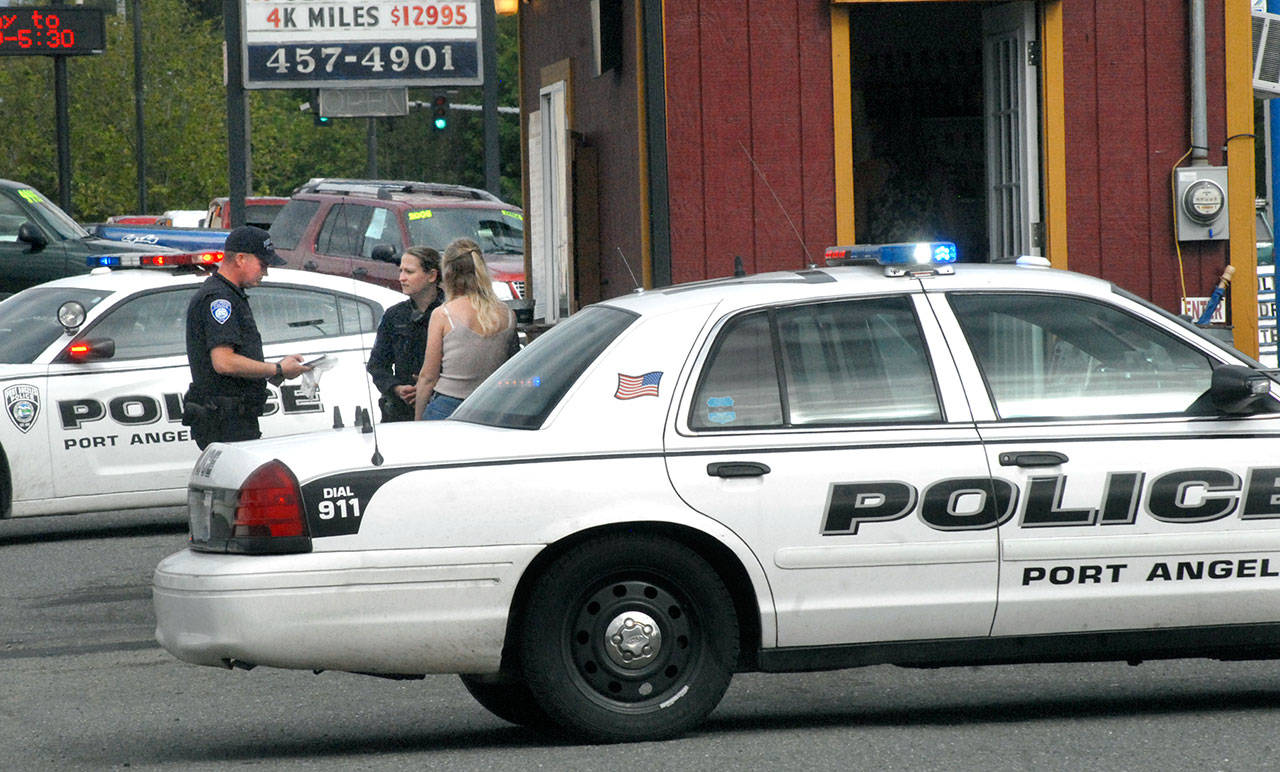 Port Angeles Police Officer Brian Stamon, left, and Sgt. Kori Malone interview a witness to an armed robbery Friday afternoon at The Daily Grind coffee stand at 1919 E. First St. in Port Angeles. (Keith Thorpe/Peninsula Daily News)