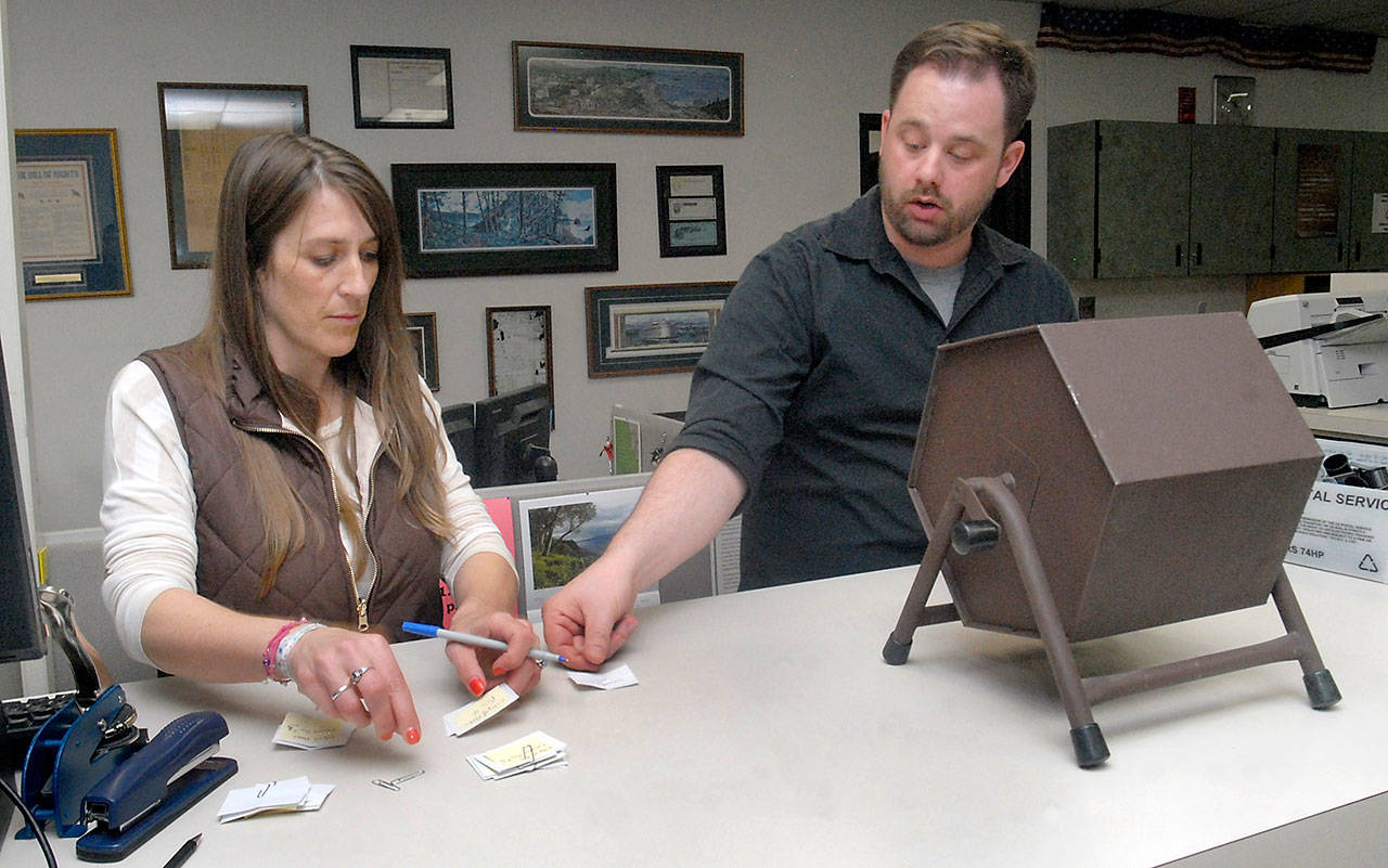 Clallam County Auditor Shoona Riggs, left, arranges slips of paper containing the names of candidates as county elections supervisor Rick Wagner pulls slips from a tumbler to determine the order names will appear on the ballot during Friday’s drawing at the Clallam County Courthouse in Port Angeles. (Keith Thorpe/Peninsula Daily News)