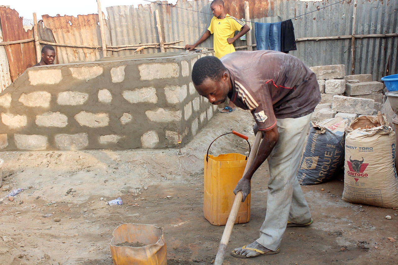 An unidentified man works on a “dignity toilet” in a village in Togo, a country in West Africa.
