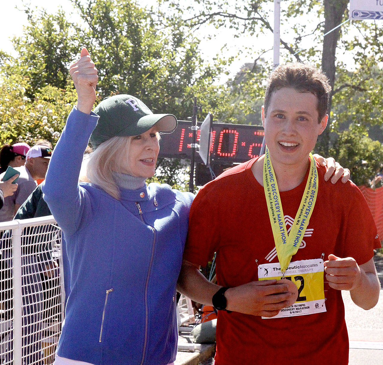 North Olympic Discovery Marathon winner Ryan Cox of Bainbridge Island is welcomed by Port Angeles City Councilwoman Cherie Kidd at the finish line. (Dave Logan/for Peninsula Daily News)