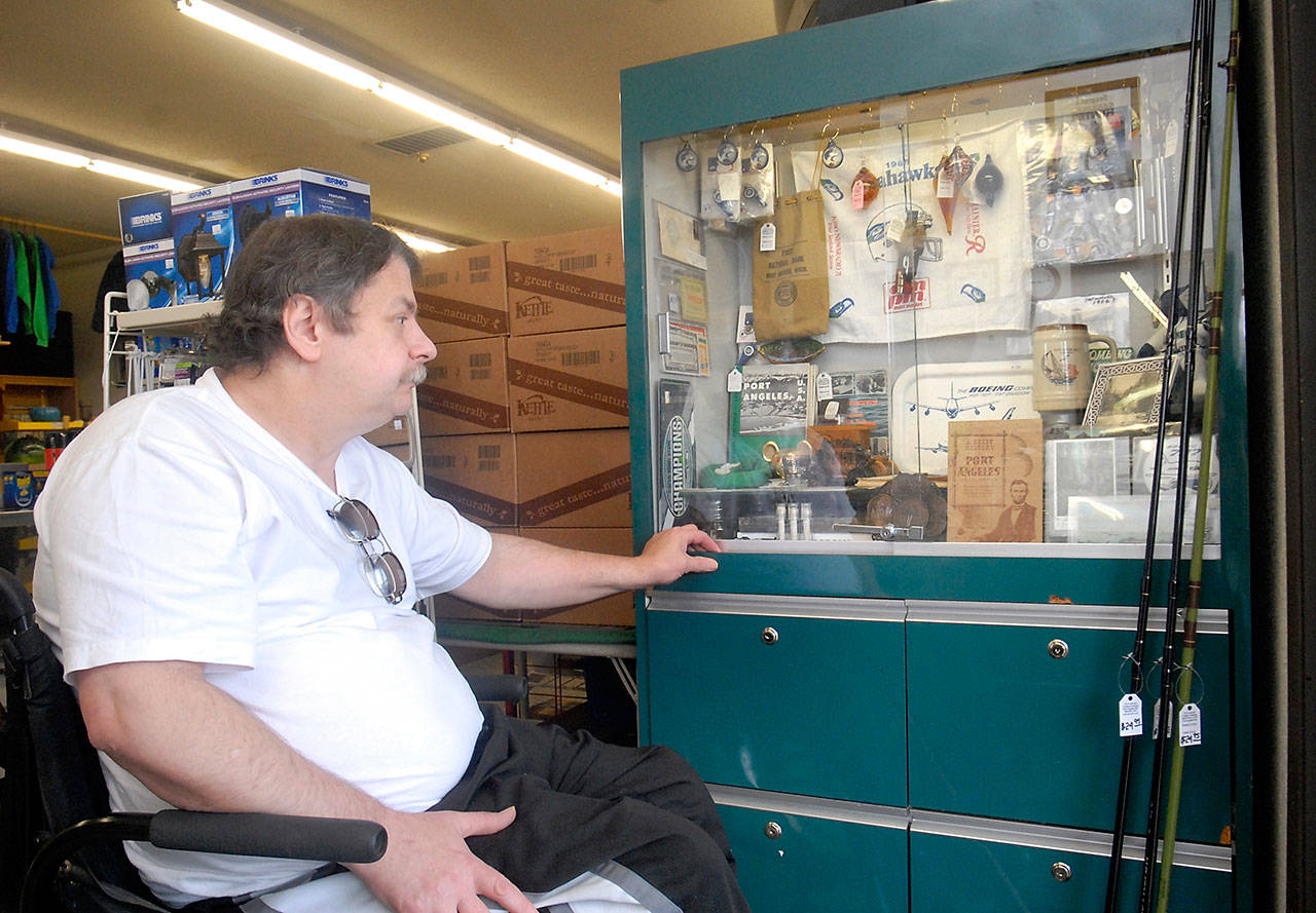 Douglas Schwab, owner of Port Crescent Trading Co. in Joyce, looks over a display of regional memorabilia left behind after his store was burglarized between last Tuesday evening and Wednesday morning. (Keith Thorpe/Peninsula Daily News)