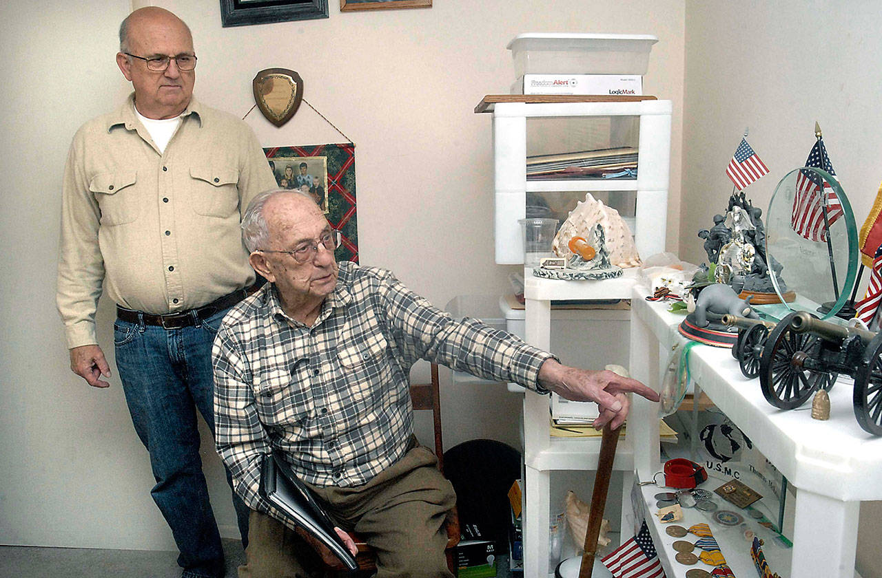 Tom McKeown Jr., left, looks on as his father, Tom McKeown Sr., points out memoribilia from his military service in World War II. The Port Angeles men, both of whom served in the U.S. Marine Corps, will ride aboard a vintage B-17 bomber aircraft during a visit by the Wings of Freedom on Wednesday at William R. Fairchild International Airport in Port Angeles. (Keith Thorpe/Peninsula Daily News)
