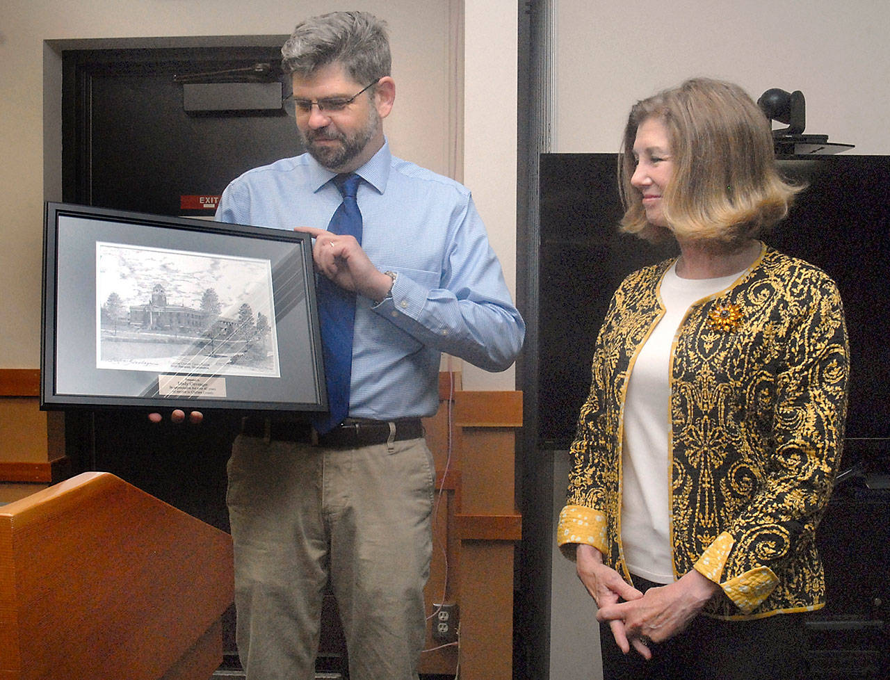 Clallam County Commissioner Mark Ozias, left, presents an etching of the county courthouse to retiring court admistrator Melinda Clevenger as a retirement gift during Tuesday’s commissioners meeting. Clevenger’s last day in the position is Friday, capping off a 43-year career with the Clallam County court system. (Keith Thorpe/Peninsula Daily News)