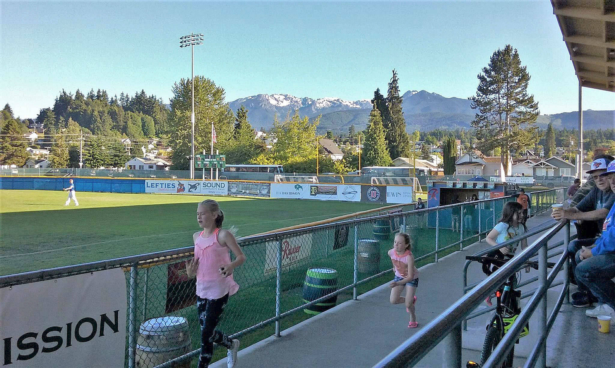 The Olympics tower over Civic Field as kids enjoy a Lefties home game last week. (Pierre LaBossiere/Peninsula Daily News)