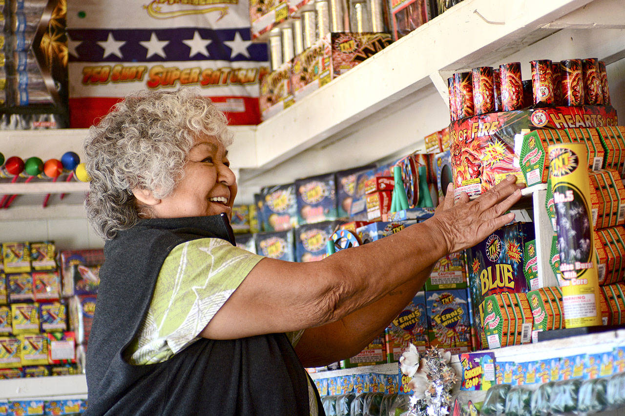 Margie Macias arranges fireworks at her fireworks stand, Margie Fireworks, on the Lower Elwha Klallam Tribe reservation on Tuesday. State-licensed fireworks stands can begin selling fireworks at noon today. (Jesse Major/Peninsula Daily News) 