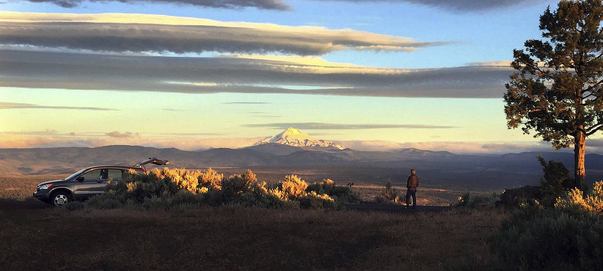 Joe Krenowicz, executive director of the Madras-Jefferson County Chamber of Commerce, looks toward Mount Jefferson as the sun rises over Madras, Ore., on June 13. (Gillian Flaccus/The Associated Press)