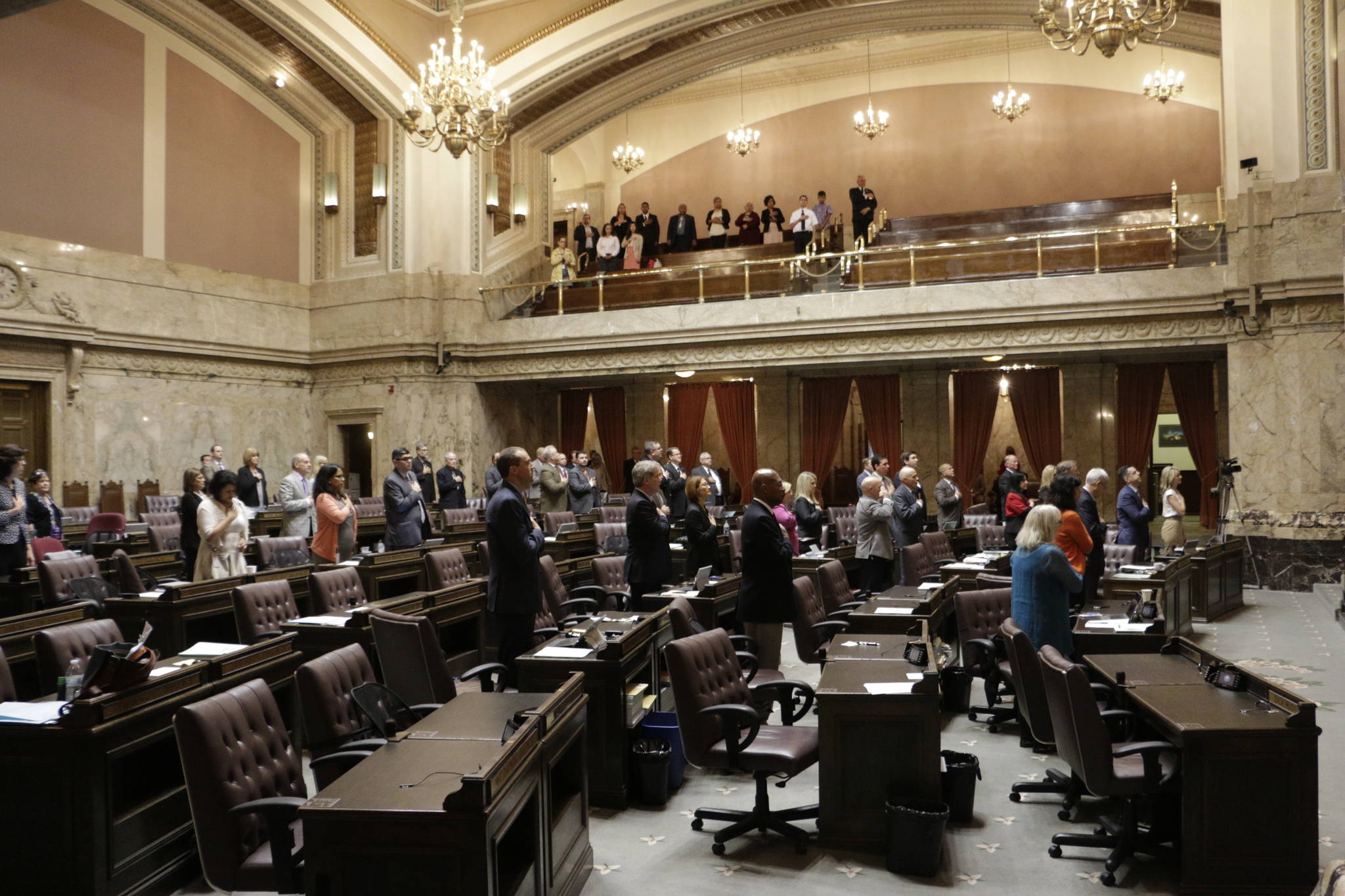 Lawmakers at the House stand during the Pledge of Allegiance on Tuesday in Olympia. The Legislature must send a new two-year budget this week or else risk a partial government shutdown. (Rachel La Corte/The Associated Press)