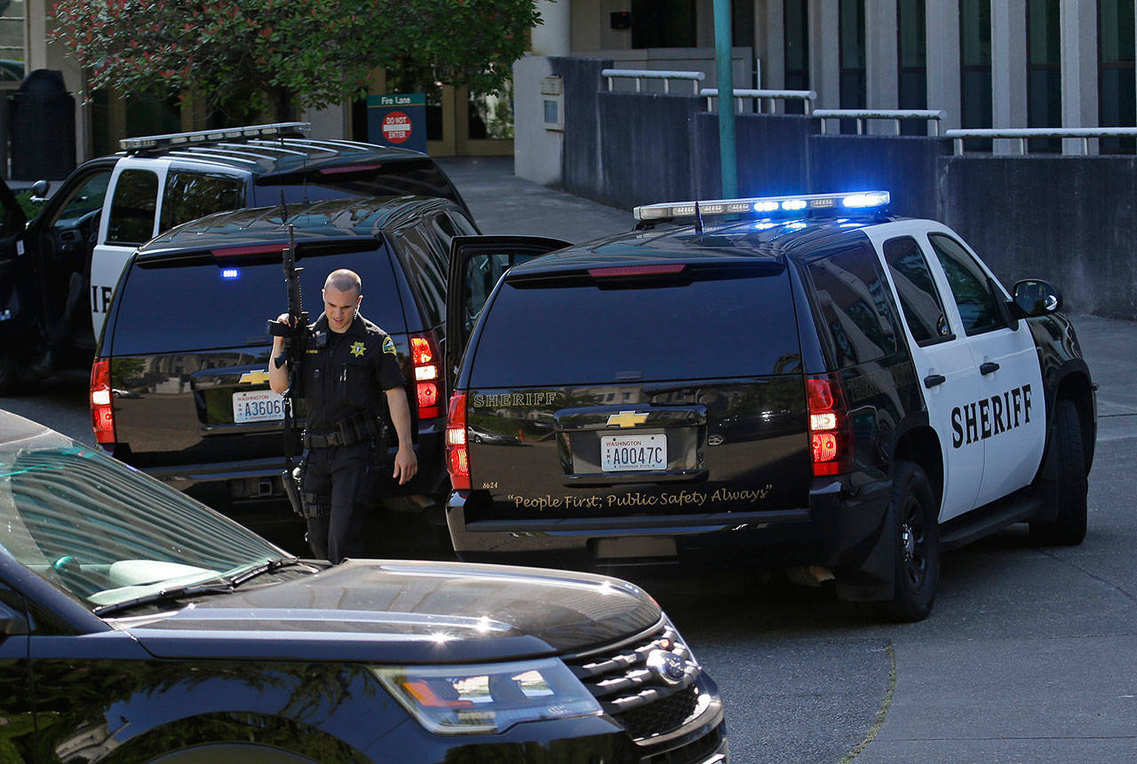 A Thurston County Sheriff’s deputy walks with a gun after a lockdown at the state Capitol campus in Olympia was lifted Wednesday. (Ted S. Warren/The Associated Press)