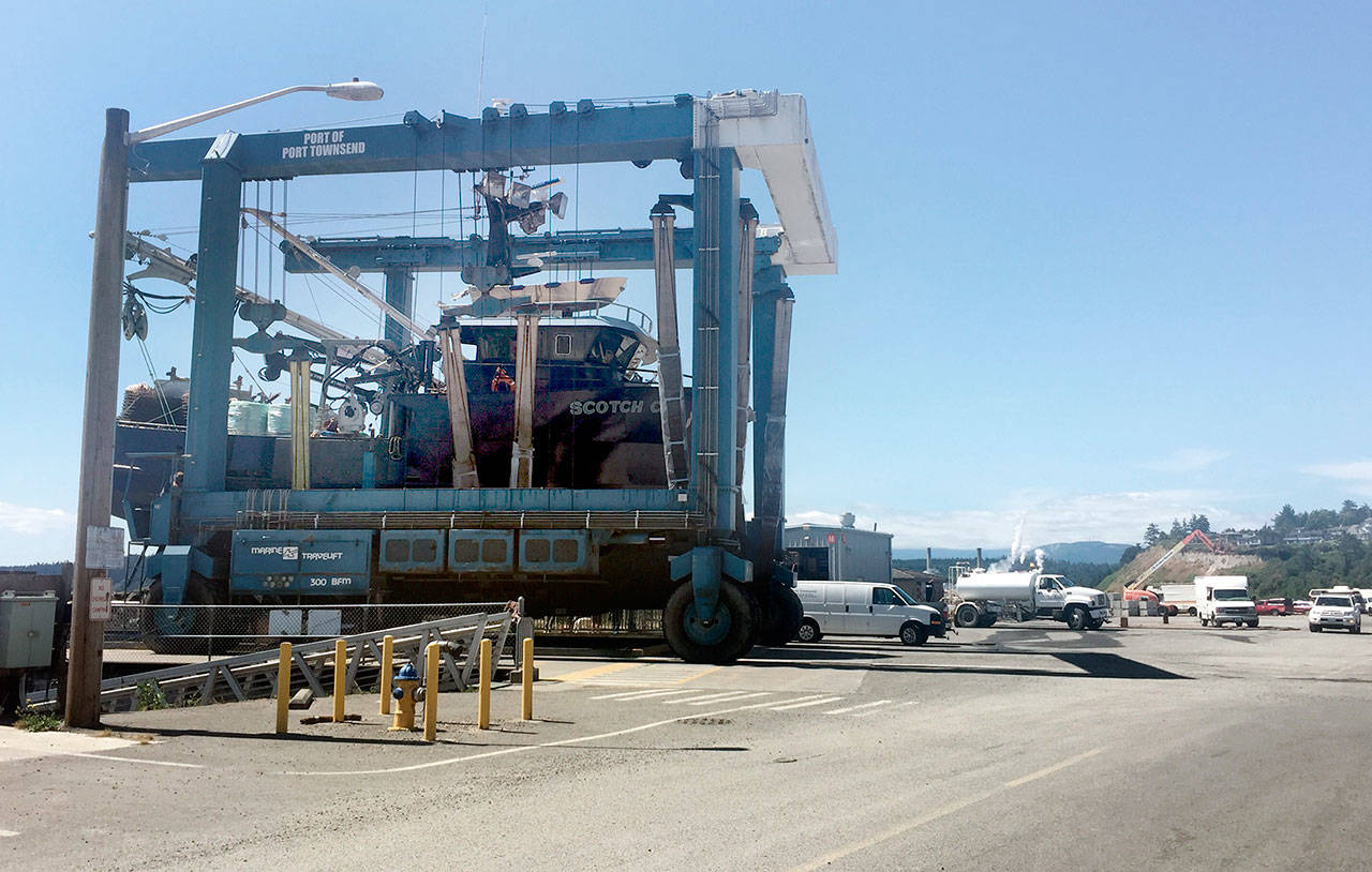 A lift carries a fishing boat across the workyard at Boat Haven Marina. The yard is scheduled to be resurfaced by Sept. 1 to cut down on dust. (Cydney McFarland/Peninsula Daily News)