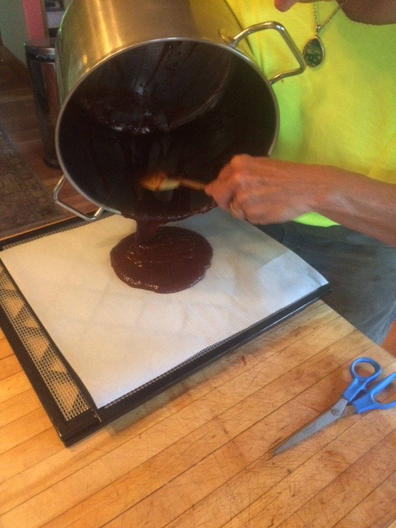Betsy Wharton pours pureed fruit onto parchment paper to then dehydrate it for homemade fruit leather. (Betsy Wharton/for Peninsula Daily News)