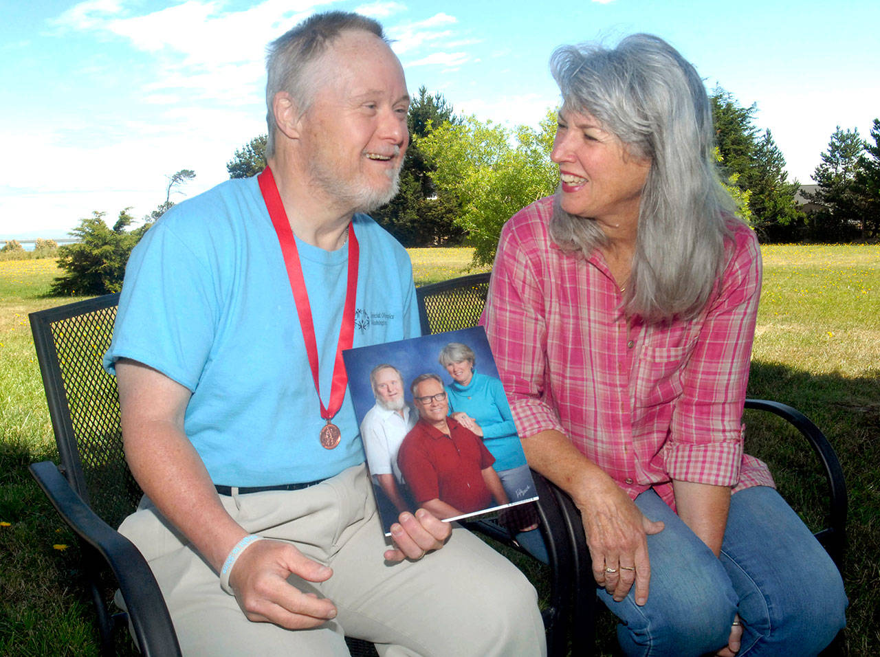 David Dow, left, holds a family photo as he sits with his sister, Mary Jane Duncan, the widow of Bob Duncan, in photo, at their rural Sequim home Saturday. (Keith Thorpe/Peninsula Daily News)