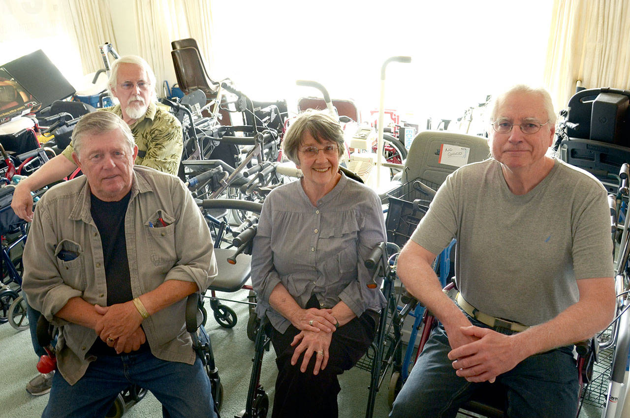 ECHHO volunteer Richard Heitman, Executive Director Sarah McMahan, and volunteers Jeffery Hall and Walt Hill sit in a room full of walkers that are lent out for free to ECHHO clients. (Cydney McFarland/Peninsula Daily News)