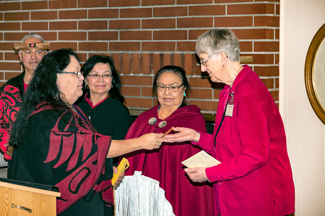Priscilla Hudson receives a cedar strip from Medicine Woman Marie Riebe as daughter Judy Cathers and Quileute tribal member Vince Penn look on. The strip was given to Hudson for her research and discovery of the canoe’s owner, Viola Riebe, second from right.