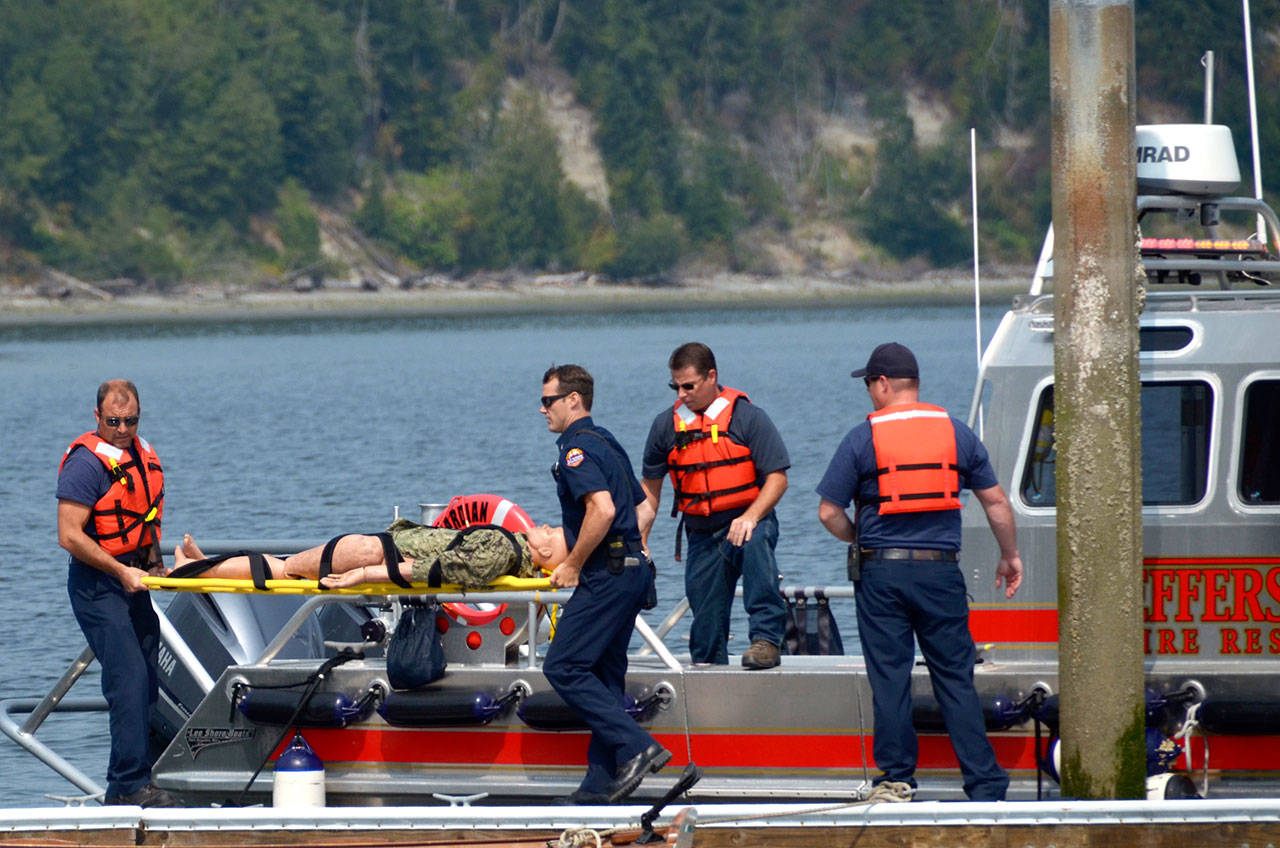 East Jefferson Fire-Rescue medics Alex Morris and Reese Chambers carry a 120-pound dummy to the beach to use for an emergency exercise at Kala Point on Wednesday. (Cydney McFarland/Peninsula Daily News) ​