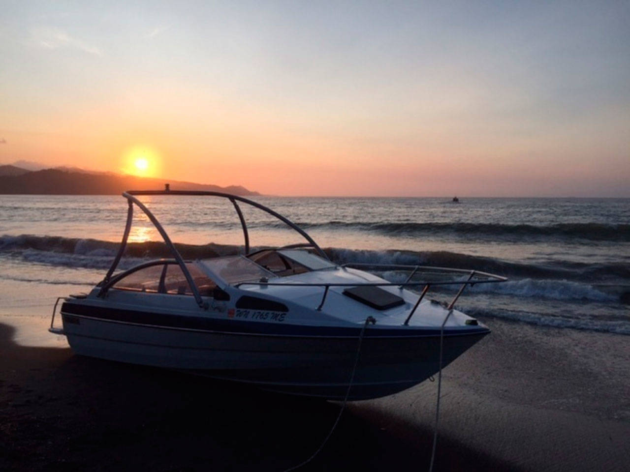 A 22-foot recreational boat sits on a beach at Kydaka Point near Neah Bay on Sunday. A ground party from Coast Guard Station Neah Bay rescued two boaters after the boat lost power and ran aground. (Petty Officer 3rd Class Corey Castillo/U.S. Coast Guard)