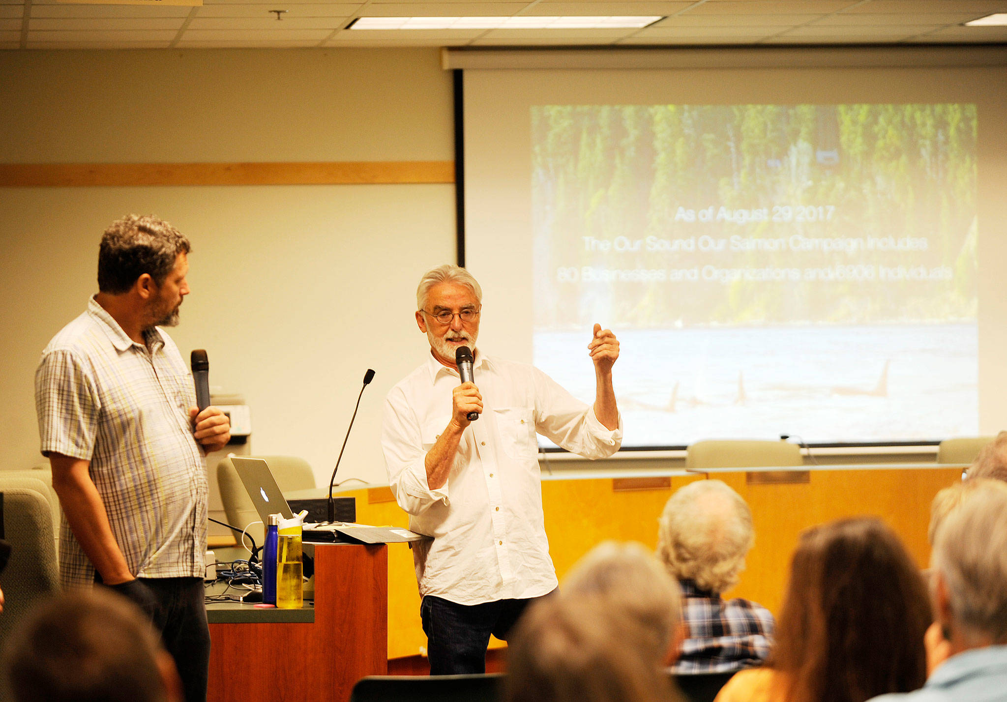 As Chris Wilke, executive director of Puget Soundkeeper Alliance, looks on at left, Kurt Beardslee, executive director of Wild Fish Conservancy, talks with Peninsula residents in Sequim on Tuesday about impacts of Atlantic salmon net pens. (Michael Dashiell/Olympic Peninsula News Group)