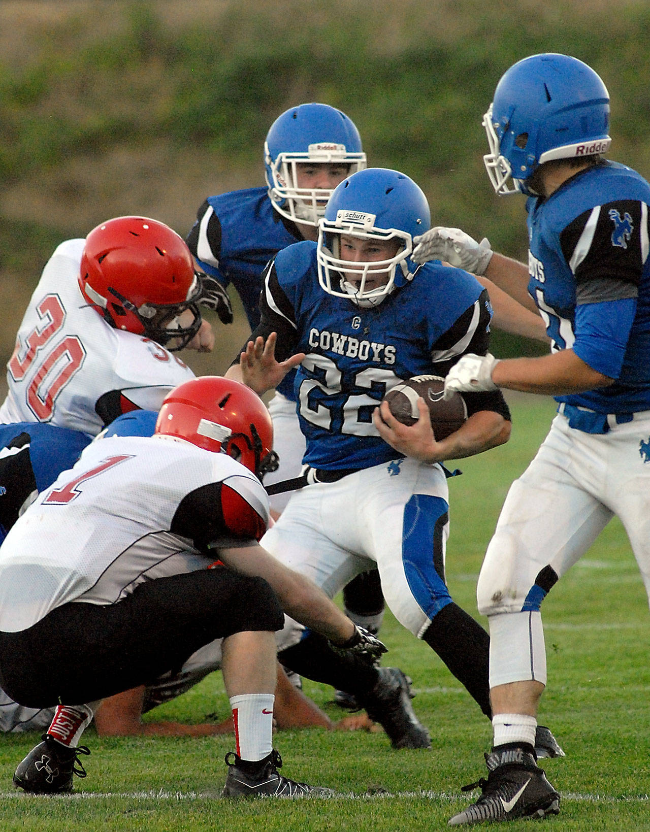 Chimacum’s Logan Shaw (22) tries to elude the defense of Neah Bay’s Daniel Kilmer (30), left, and Meric Soeneke (1) after receiving blocking assistance from teammates Ryan Caldwell (55), back, and Matthew Bainbridge (31), right, in the first quarter of Chimacum’s 21-6 victory. Keith Thorpe/Peninsula Daily News